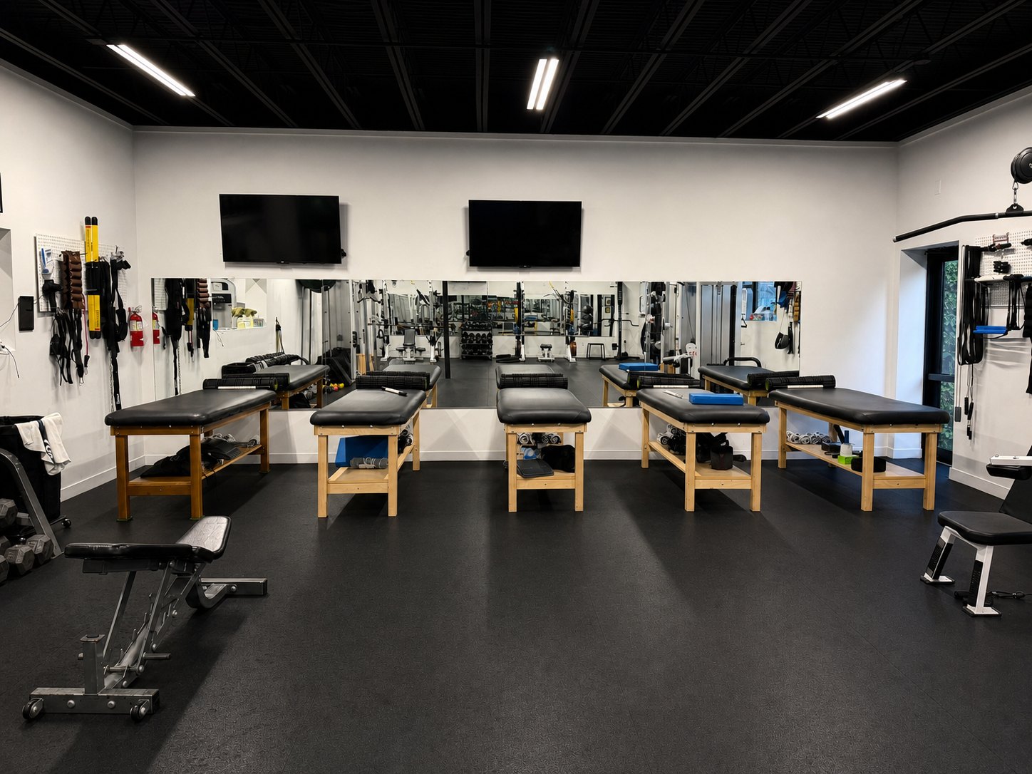 The Total Form Fitness floor &mdash; treatment and stretching tables along the mirror wall, ready before the first session